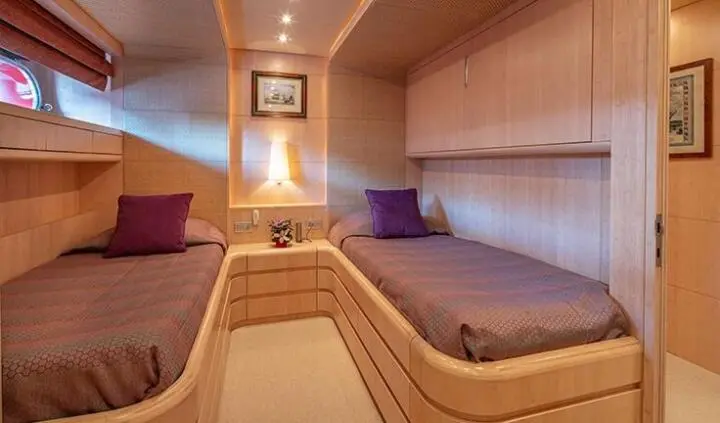 Interior cabin of a yacht with curved wood benches and purple cushions