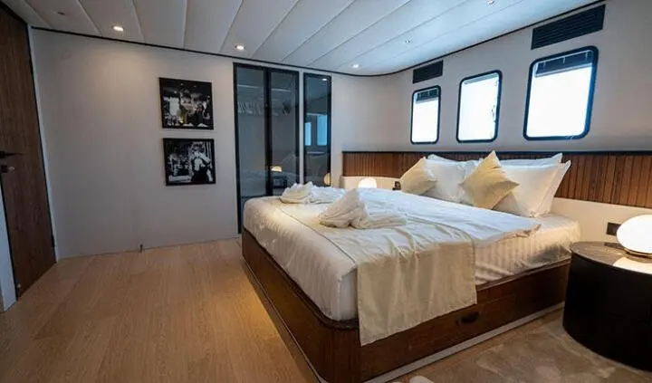 Master cabin with two single beds pushed together, beige bedding, wood floor