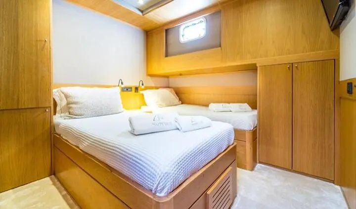 Twin-berth cabin interior with wooden cabinetry and bright bedding
