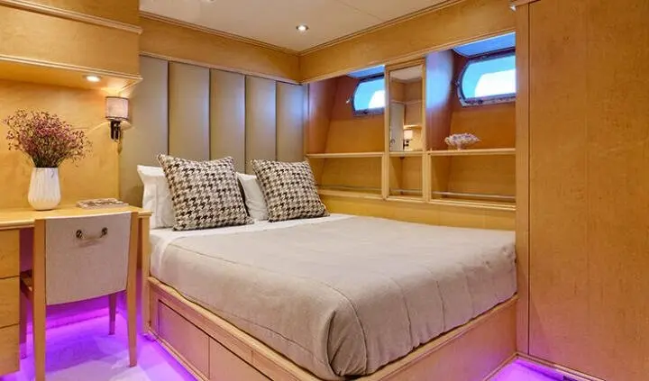 Mobius yacht master cabin with king bed, beige bedding, wood panels, built-in shelves