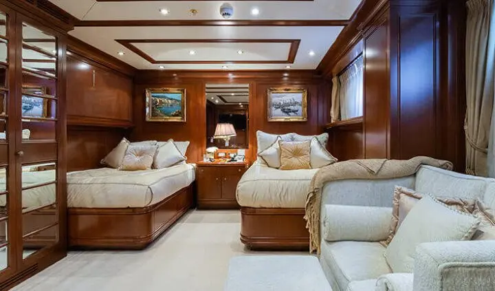 Interior of Apogee yacht cabin with twin beds, wood panels, and seating