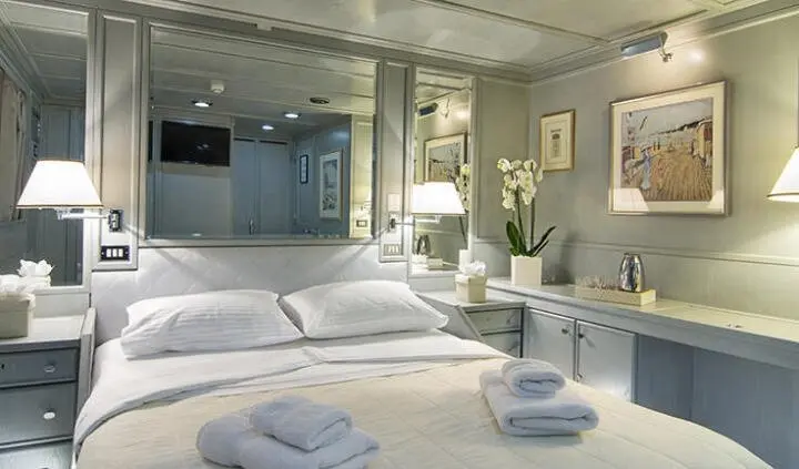Master cabin with king bed, white bedding, wood accents, ensuite visible