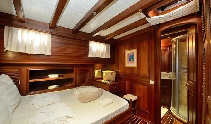 Samarkand cabin interior with wooden panels, twin beds, and porthole light