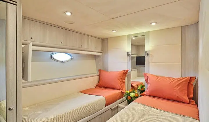 Twin-cabin berth with red cushions and compact ensuite area on yacht M Five