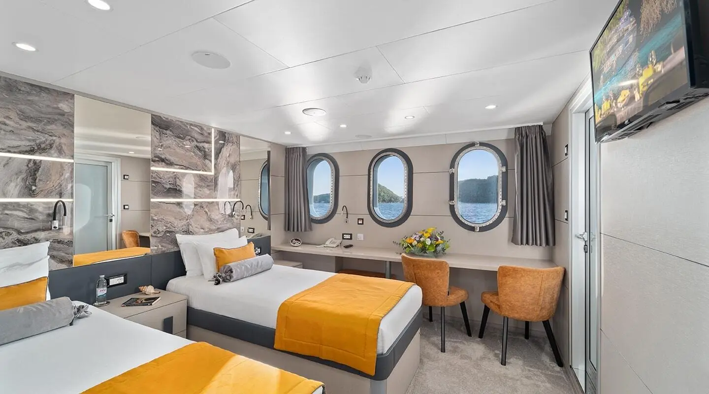 Interior of yacht Freedom with seating, round windows, and warm lighting
