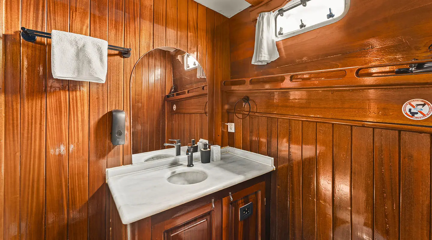Sunlit wooden interior of a yacht with a dining table set for two