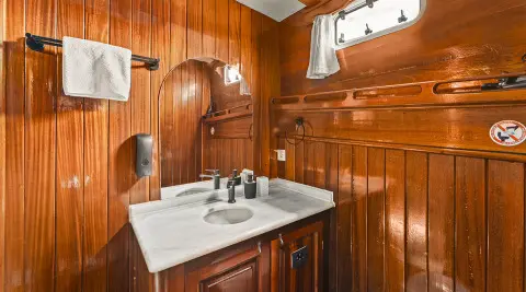 Sunlit wooden interior of a yacht with a dining table set for two