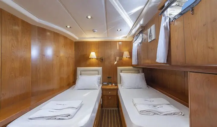 Twin cabin aboard Queen Of Sea yacht with two single beds and wooden walls