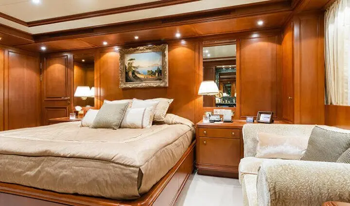Master cabin with king bed, wood panels, bedside lamps, and ensuite