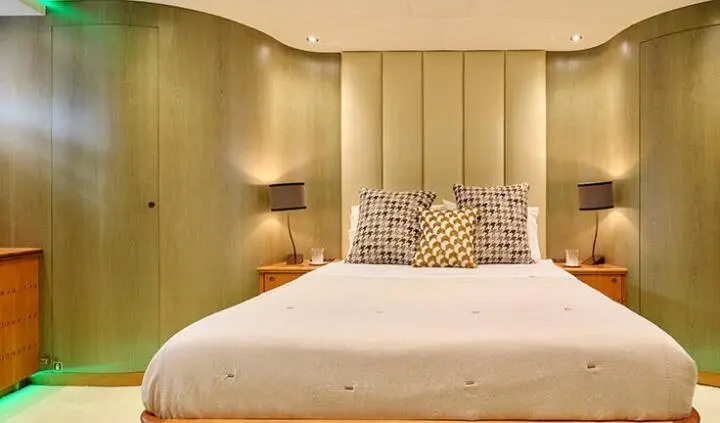 Mobius yacht cabin with a king bed, beige headboard, and patterned pillows