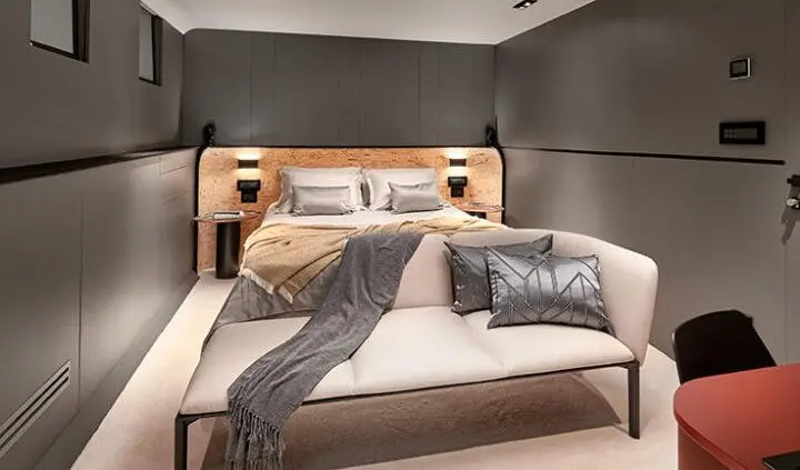Master cabin with king bed, gray upholstered walls, and plush pillows