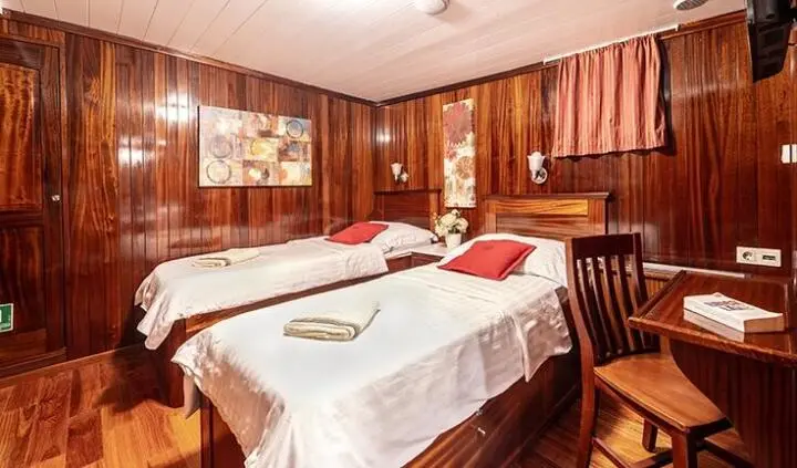 Cesarica cabin interior with two single beds, wood paneling, and warm lighting