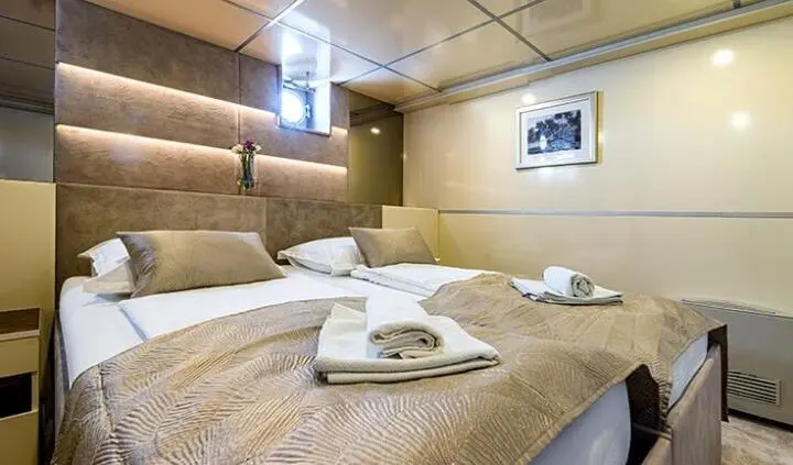 Melody yacht master cabin with king bed, neutral tones, bedside lamps, towels on bed