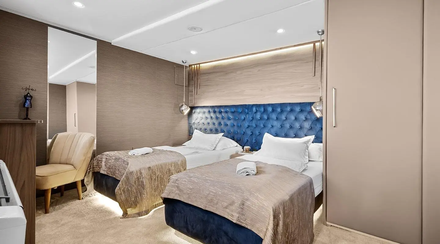 Bella yacht charter bedroom with two single beds, blue padded headboard