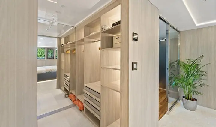 Master cabin closet interior with wooden shelves and hanging space on yacht