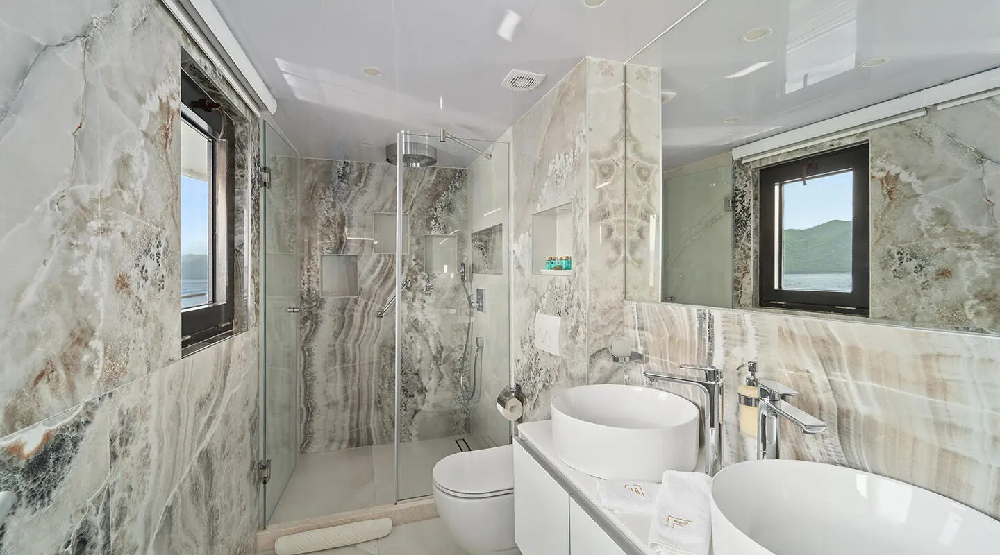 Luxurious yacht Freedom bathroom with glass shower, marble walls, and white fixtures