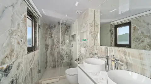 Luxurious yacht Freedom bathroom with glass shower, marble walls, and white fixtures