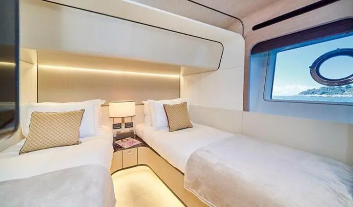 Twin cabin with two single beds, bright bedding, and overhead storage on yacht Aluminia Too
