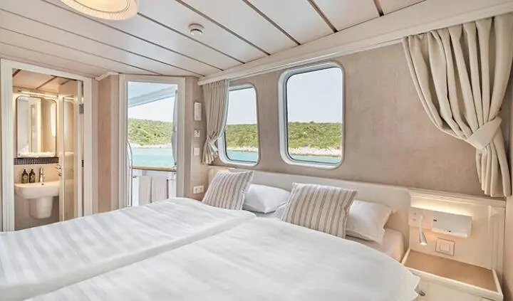 La Perla yacht cabin interior with plush double bed and sea-view windows