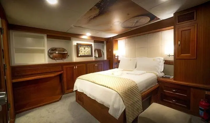 Two single beds in a cabin with brown wood paneling and warm lighting