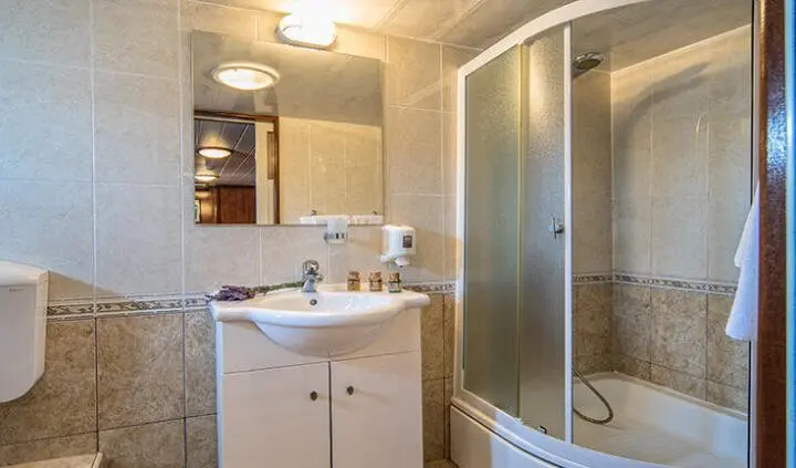 Bathroom on Luna yacht cabin with sink, mirror, and curved shower enclosure
