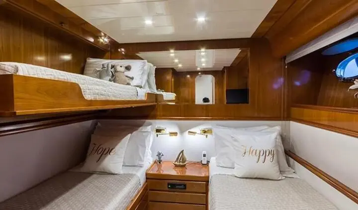 Twin bunk cabin on Amoraki yacht with wood paneling and white bedding