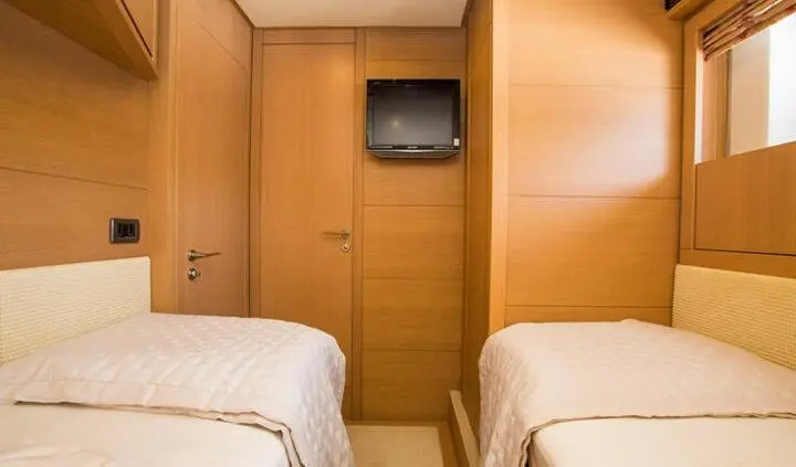 Twin cabin with beds, wood walls, and a small wall-mounted TV