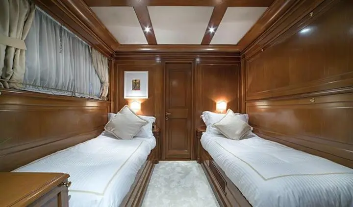 Aquila yacht cabin interior with twin beds, wood paneling, and recessed lighting
