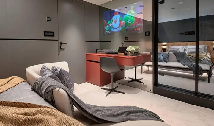 Interior cabin on Anetta yacht with a red chair, bed, TV, and large windows