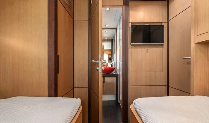 Twin cabin aboard a yacht with wood sole flooring, small beds on both sides