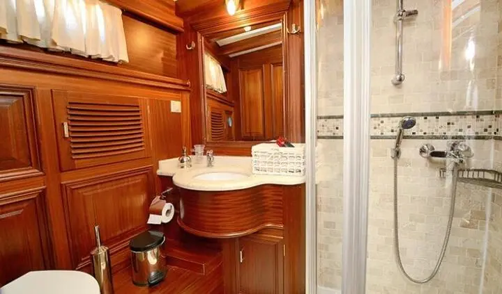 Luxurious master cabin with wooden paneling and single bed, ensuite bath visible