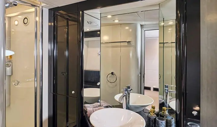 Interior view of a yacht cabin with a sink, mirror, and cabinetry