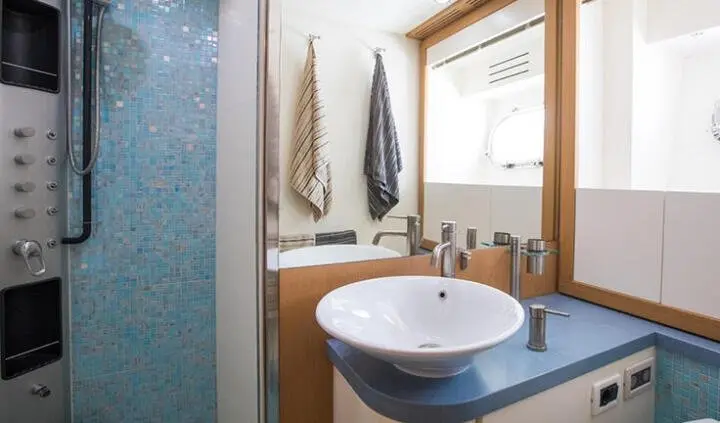 Master cabin with king bed, ensuite sink, window, and towels on rack