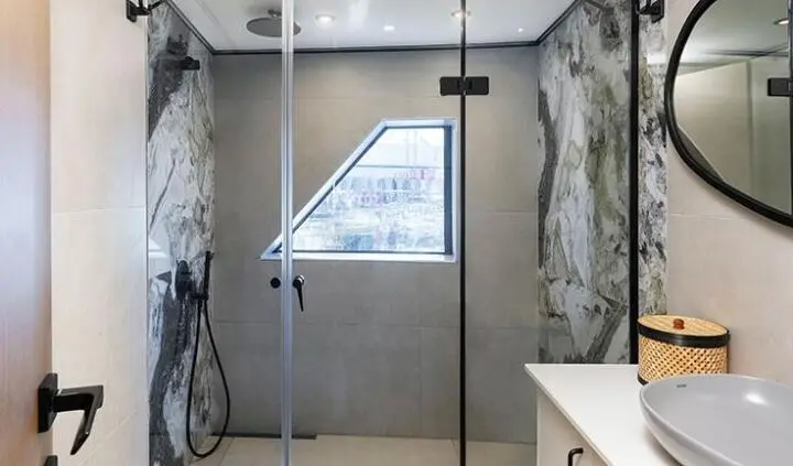 Calm Down yacht cabin with a king bed, glass shower, and marble walls
