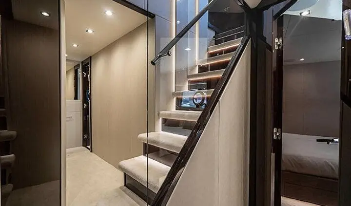 Quantum yacht cabin interior with glass staircase, beige carpeting, and adjoining bathroom