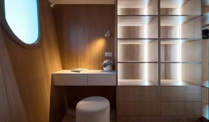Luxurious yacht cabin with king bed, ensuite area, warm wood tones, bedside lamp