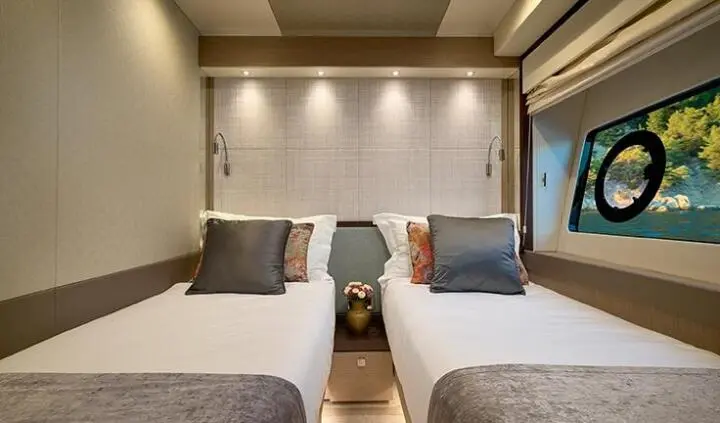 Twin cabin with two beds, shared upholstered headboards and soft lighting
