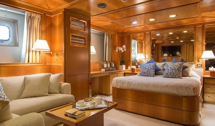 Opulent yacht master cabin with king bed, wood paneling, and ambient lighting