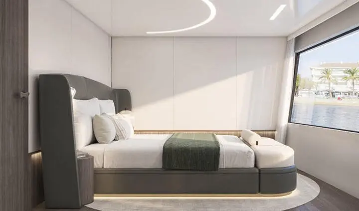 Bello yacht cabin with king bed, white and green bedding, sunlit scene