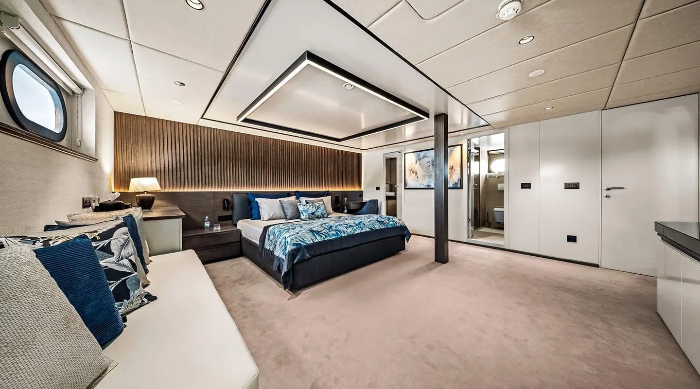 Anima Maris master cabin interior: plush blue bed, wooden accents, ceiling lighting