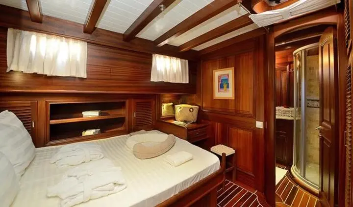 Double cabin with two single beds, wood paneling, overhead shelves, warm lighting