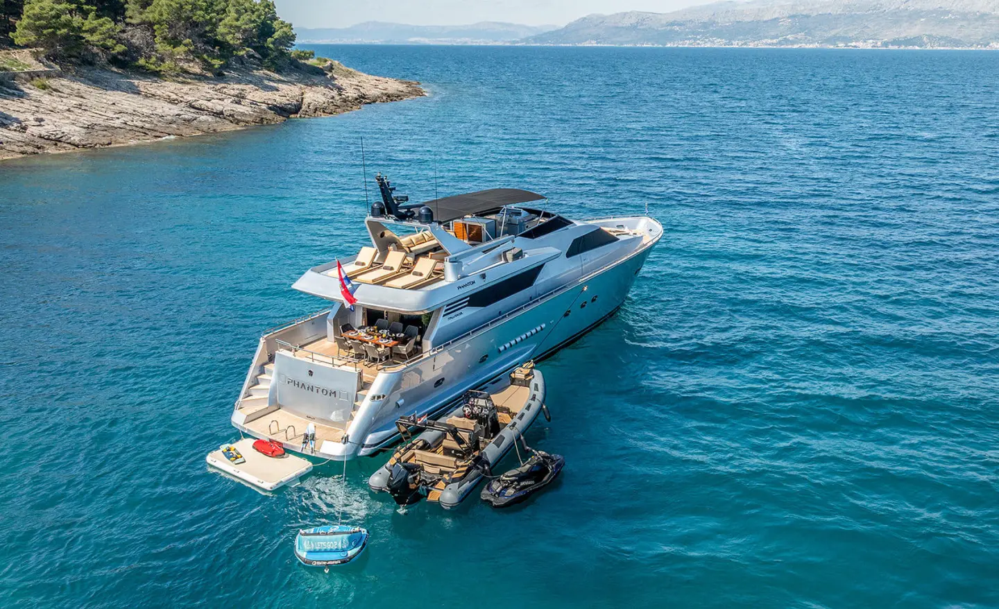 Phantom motor yacht anchored in blue water with people on board