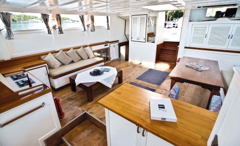 Interior of the yacht with sofa, table, and wooden flooring, white cabinets