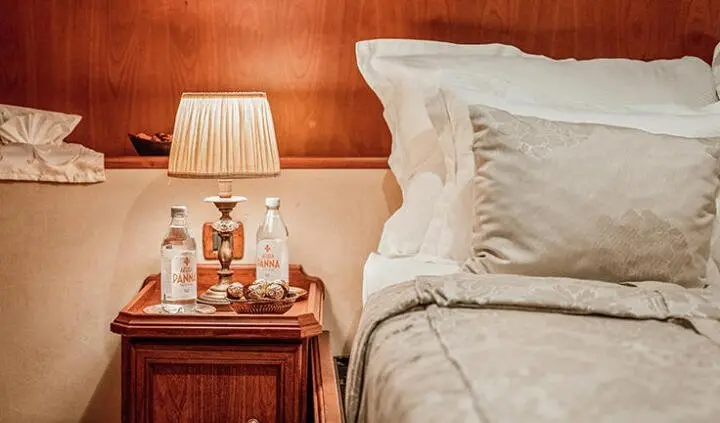 Seagull II cabin master bed with white pillows and warm bedside lamp