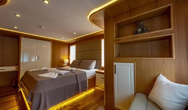 Master cabin with king bed, wood paneling, ensuite doorway, soft lighting