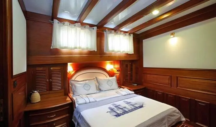 Master cabin with king bed, wood panels, porthole windows, and ensuite area