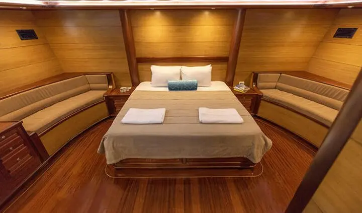 Master cabin with king bed, wooden floors, bedding and overhead lighting