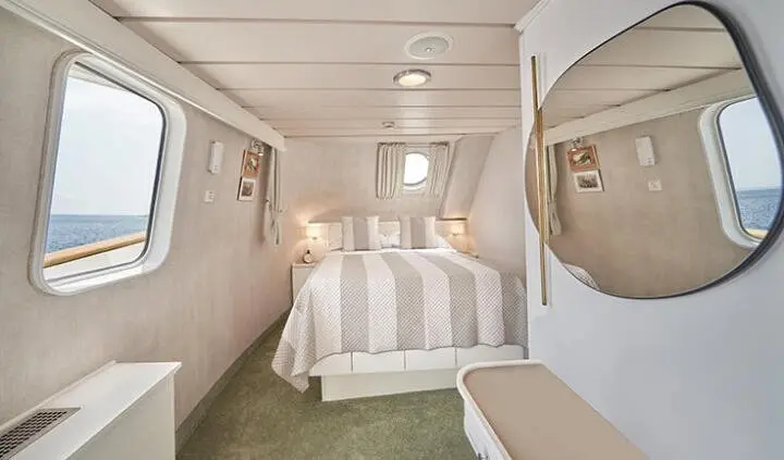 Master cabin with king bed, striped bedding, overhead lights, and seating area