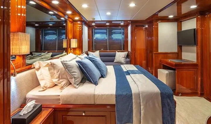 Luxurious yacht cabin with king bed, blue striped bedding, and wooden cabinetry