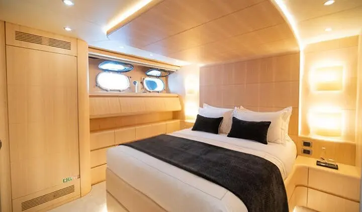 Pareaki II master cabin with king bed, white bedding, wood paneling, and porthole windows